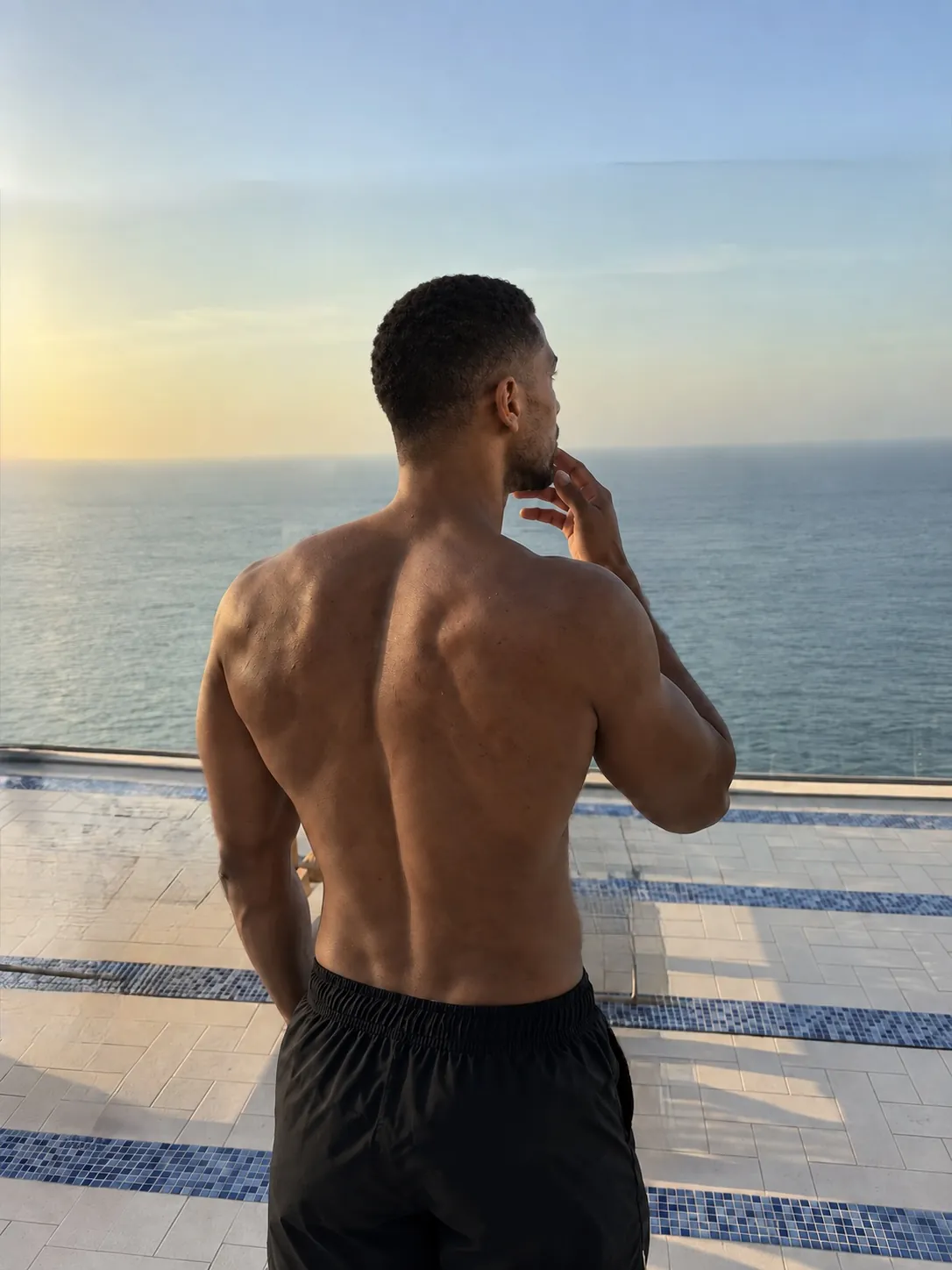 Ayo from behind on a terrace, looking out over the Atlantic at sunrise